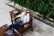 © Eloisa Ramos/Westend61 - Senior female professional listening music while relaxing on chair at garden