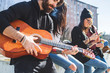 © © Eugenio Marongiu/Westend61 - Man smoking cigarette playing guitar while chilling with friends in city