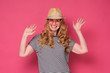 © Viktor Koldunov - Beautiful mature woman wear sunglasses and hat smiling and waving palm saying hello. Enjoy summer holiday isolated on pink background.