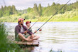 © Vasily Pindyurin/Westend61 - Father and son fishing while sitting on boardwalk at riverbank
