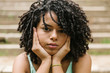 © Xavier Lorenzo/Westend61 - Portrait of curly young woman with hands on chin