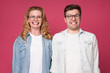 © Viktor Koldunov - Funny caucasian woman and man smiling happily while looking at camera, standing over pink background