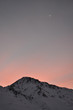 winter sunset over snowy mountain and the moon in the background