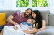 © CandyRetriever  - Beautiful Caucasian mother and father with newborn baby son are resting together on sofa in living room. Mom holding sleeping cute infant child boy. Happy Family, parenthood and healthcare concept.