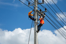 An Electrician Is On A Light Pole To Maintain A High Voltage Line On A Dangerous Electric Pole.