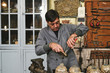 © Cien X Cien Studio/ADDICTIVE STOCK - Focused middle aged ethnic craftsman in uniform using pincers while working with golden stick near various vases behind wall with tools in workshop