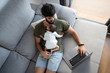 © Fran Rosado/ADDICTIVE STOCK - From above male freelancer holding baby while lying on sofa and working on project with netbook at home
