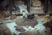 Dirty Boot Placed On Concrete Floor And Surrounded By Dusty Clothes In Shabby Facility Of Neglected Plant