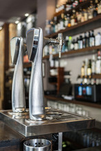 Metallic Beer Column Placed On Bar Counter Against Shelves With Alcoholic Drinks In Glass Bottles