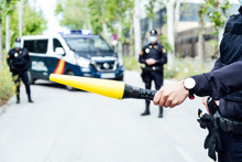 Crop Anonymous Police Officer Prohibiting Car Driving On Street With Yellow Traffic Baton During Coronavirus On Sunny Day