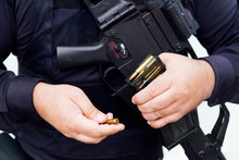 Crop Chubby Anonymous Police Officer In Dark Uniform Showing Golden Bullet Made Of Lead And Brass Materials While Holding Firearm In Daylight