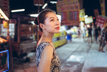 Side View Of Confident Ethnic Female Standing On Crowded Street In Night Market In Taiwan And Looking Away