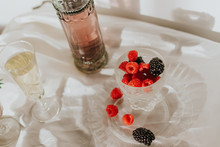 From Above Beautiful Composition With Vintage Styled Bottle And Glasses On White Table Arranged With Plate And Goblet With Berries