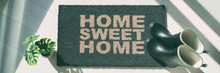 Autumn Rain Boots At Home Door Entrance Home Sweet Home Mat Banner. Panoramic Background Of Shoes Left At House Doormat.