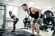 © Vadim - Sport, bodybuilding, lifestyle and people concept - young man and woman with barbell flexing muscles and making shoulder press squat in gym. Trainer and fitness girl are having workout at gym.