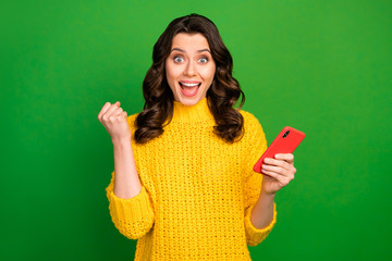 Surprised crazy energetic girl use smartphone celebrate her online social media lottery win raise fists scream yes wear winter knitted style jumper isolated bright shine color background