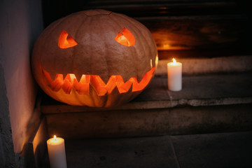 Happy Halloween. Halloween street decor with spooky Jack-o'-lantern. Pumpkin with scary carved glowing face and candle light in dark, modern festive decoration.