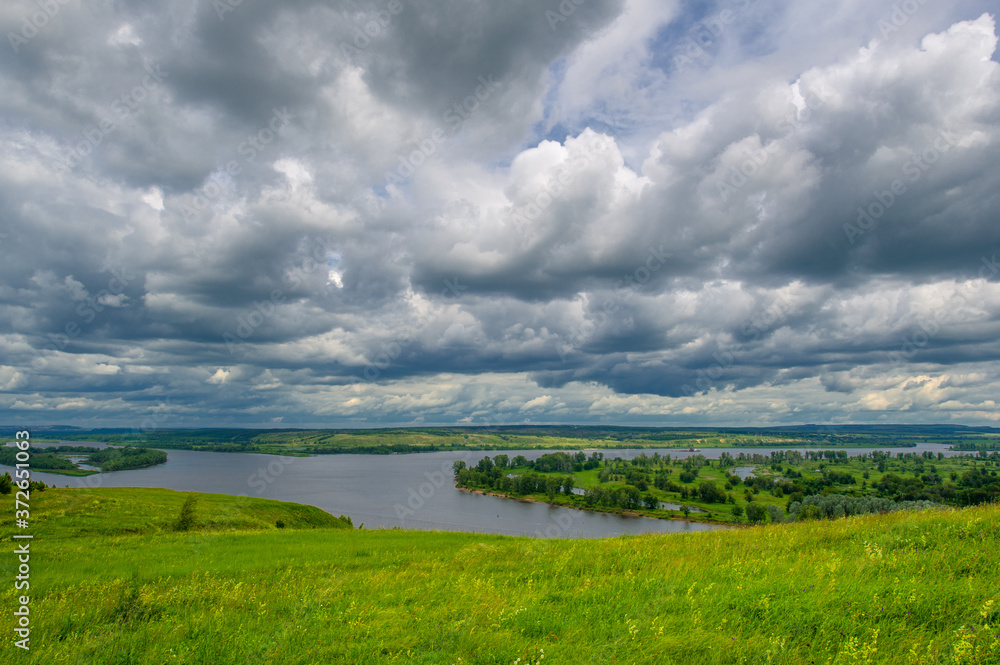 Summer landscape, a large full-flowing river, meadow flowers on the banks of the river, mighty clouds in the sky, a tourist walk along the Kama River - obrazy, fototapety, plakaty 