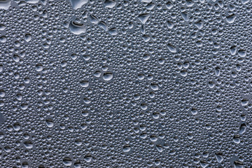 Drops of water after the rain on a glass panel with the sky above