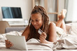 Young woman lying on bed using digital tablet and credit card she buying clothes in online shop