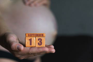 september 13th. Day 13 of month,planned date of birth. Month and day placed on wood calendar in pregnant womans hand. autumn month, day of the year concept