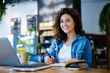 © BullRun - Portrait of successful smiling young student looking into camera while recording information in textbook and preparing for coursework.Smiling attractive hipster girl planning her week schedule
