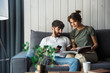 © Drobot Dean - Lovely young couple relaxing on a couch at home, reading magazine