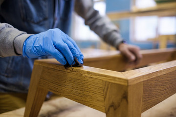 Woodwork oil being applied on wooden furniture. Close up view.