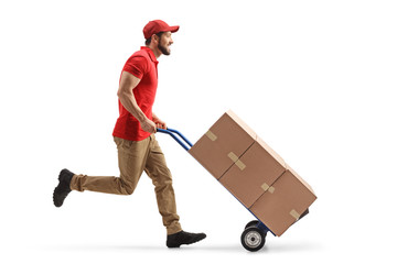 Wall Mural - Full length profile shot of a male worker running with boxes on a hand-truck