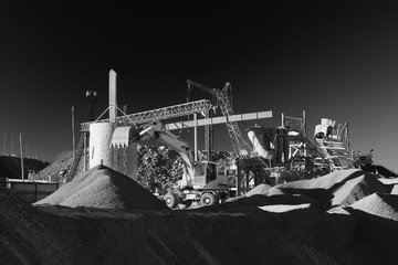 Wall Mural - Excavator on the background of stone crushing equipment in the ore processing plant, black and white.