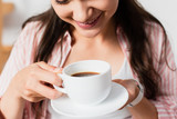 Fototapeta  - cropped view of young woman holding cup of coffee