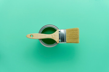 GREEN PAINT CAN AND WOODEN BRUSH ON AQUA MINT COLOUR BACKGROUND. DIY, RENOVATION AND DECORATION CONCEPT. TOP VIEW.
