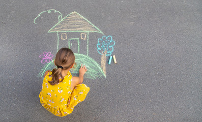 Wall Mural - The child draws a house on the asphalt. Selective focus.