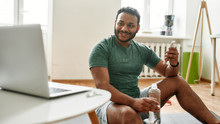 Sharing Advice. Young Active Man Smiling, Advertising Smartphone App While Streaming, Broadcasting Video Lesson On Training At Home Using Laptop. Online Personal Trainer
