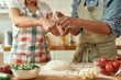 © Svitlana - Cropped shot of couple preparing the dough together. Young man and woman in apron cooking, making pizza at home. Hobby, lifestyle