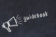 © iushakovsky - Chalk loudspeaker and inscription guidebook on black chalkboard