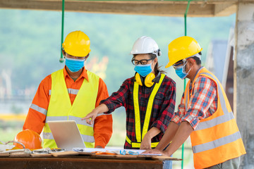 Poster - Team of engineer and architects wearing protective mask to Protect Against Covid-19 using laptop at construction site.
