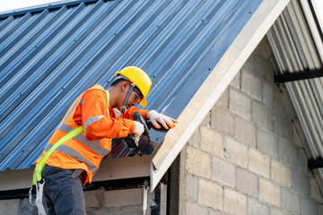 Poster - Roofer working on roof of new building,Electric drill used on new roofs with Metal Sheet.