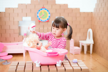 Wall Mural - young girl pretend play babysitting with baby doll at home