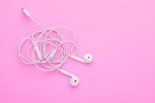 White Tangle Earphone On Pink Background. Copy Space For Text Or Design