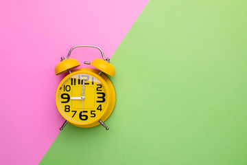 Old yellow alarm clock on bright color background