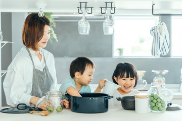 新築のリビングで母親が子供二人に料理を教えている　fmaily kids 子育て