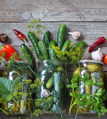 Autumn food background.We canning cucumbers for the winter. Homemade canned food with cucumbers in glass jars on a wooden background with fresh cucumbers and ingredients for pickling.