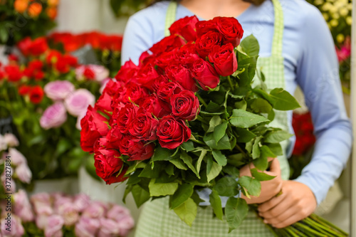 Seller with bouquet of beautiful red roses in shop