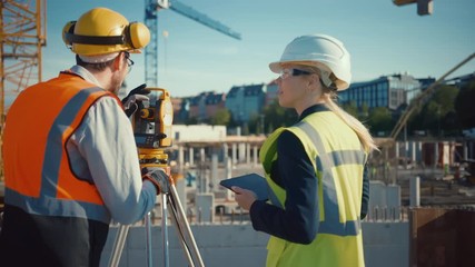 Wall Mural - Construction Worker Using Theodolite Surveying Optical Instrument for Measuring Angles in Horizontal and Vertical Planes on Construction Site. Engineer and Architect Using Tablet Next to Surveyor.