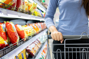 Closeup of a female hand with trolley cart shopping at supermarket. Shopping supermarket concept.