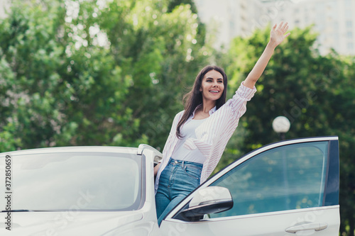 Bye-bye city escape concept. Photo of positive cheerful girl ride drive car wave hand farewell friends family start outdoors adventure