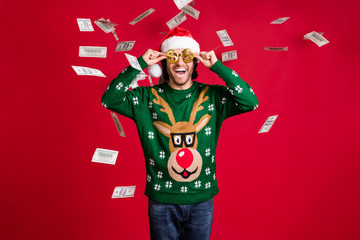 Portrait of his he nice attractive glad cheerful cheery guy wear Santa look throwing usd 100 bank deposit loan debit atm earnings salary isolated bright vivid shine vibrant red color background