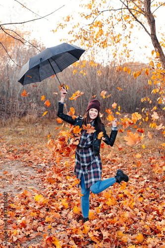 Happy woman makes rain from the leaves in autumn park.