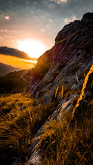 Poster - Beautiful shot of a field near cliffs with a sunset sky background